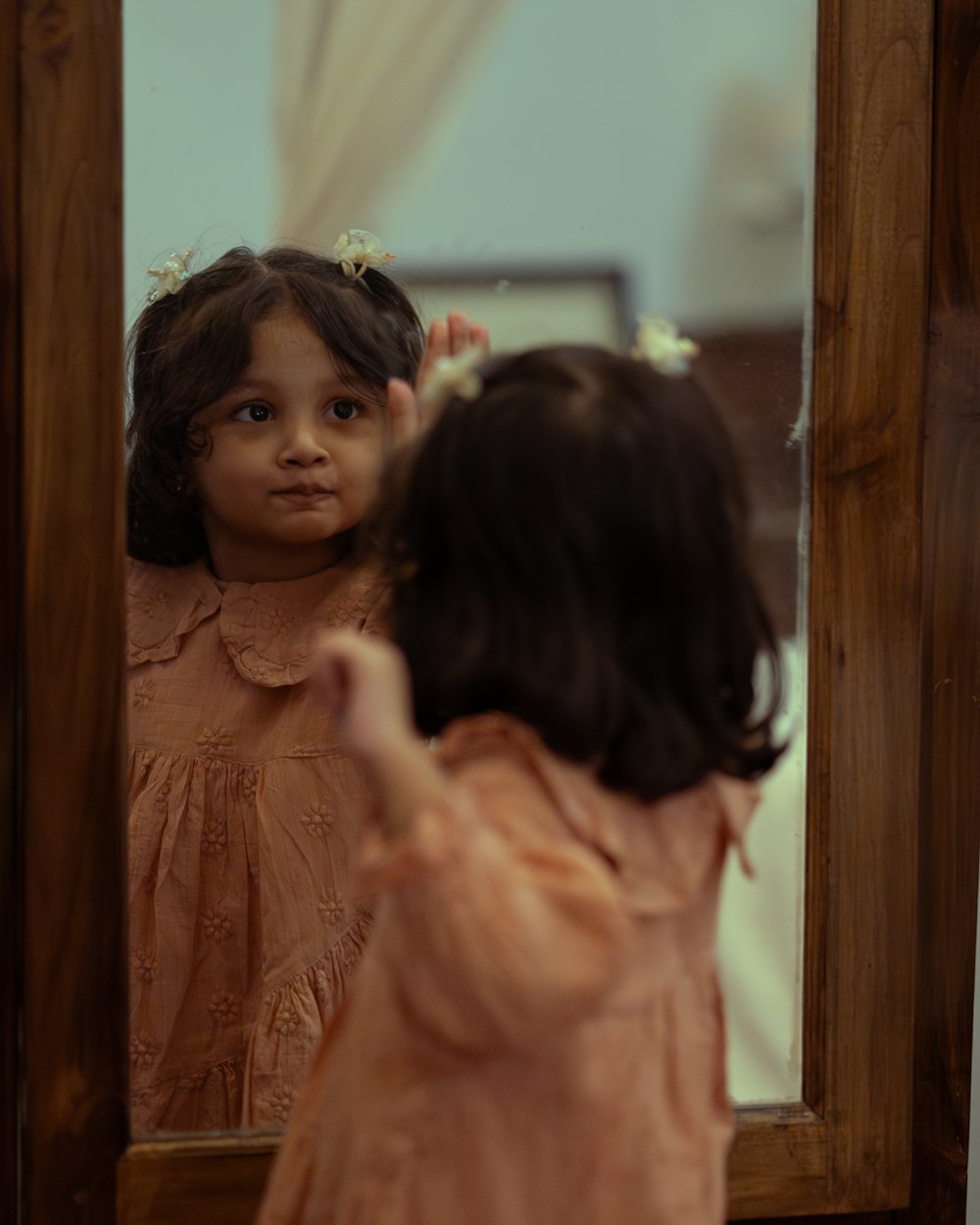 una niña pequeña parada frente a un espejo