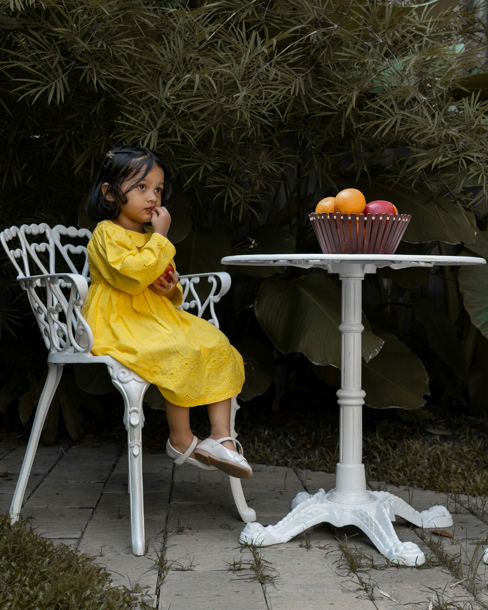 a little girl in a yellow dress sitting at a table