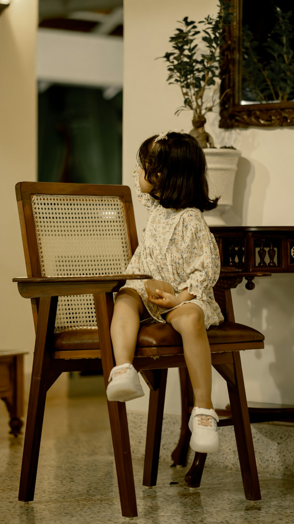 a little girl sitting on a wooden chair