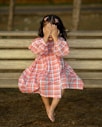 a little girl covering her face while sitting on a bench