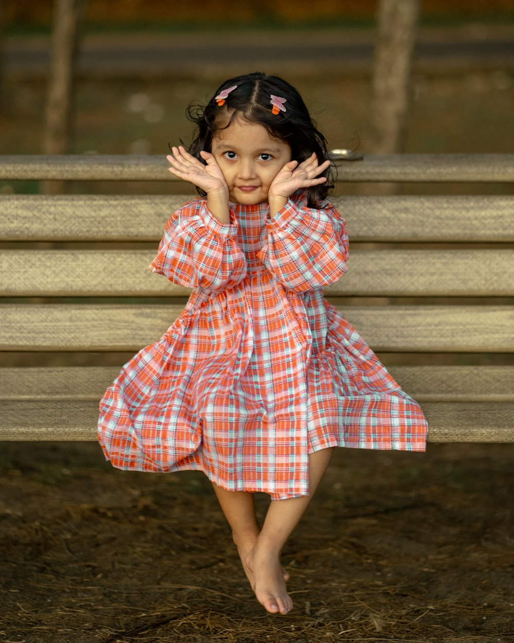 a little girl that is standing in front of a bench