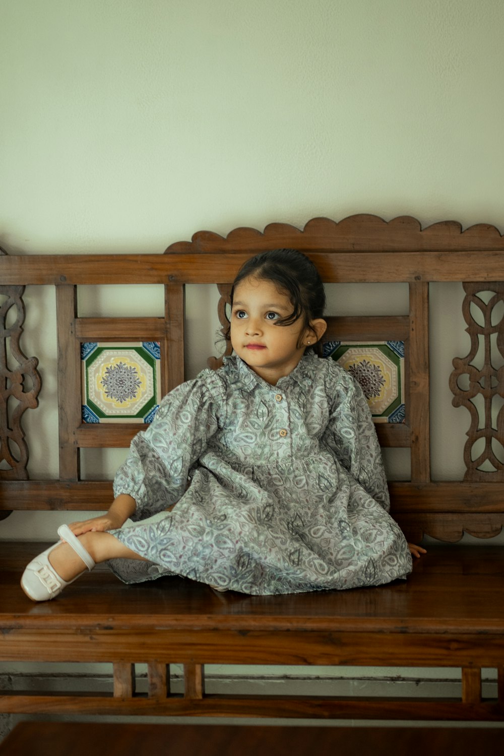 a little girl sitting on a wooden bench