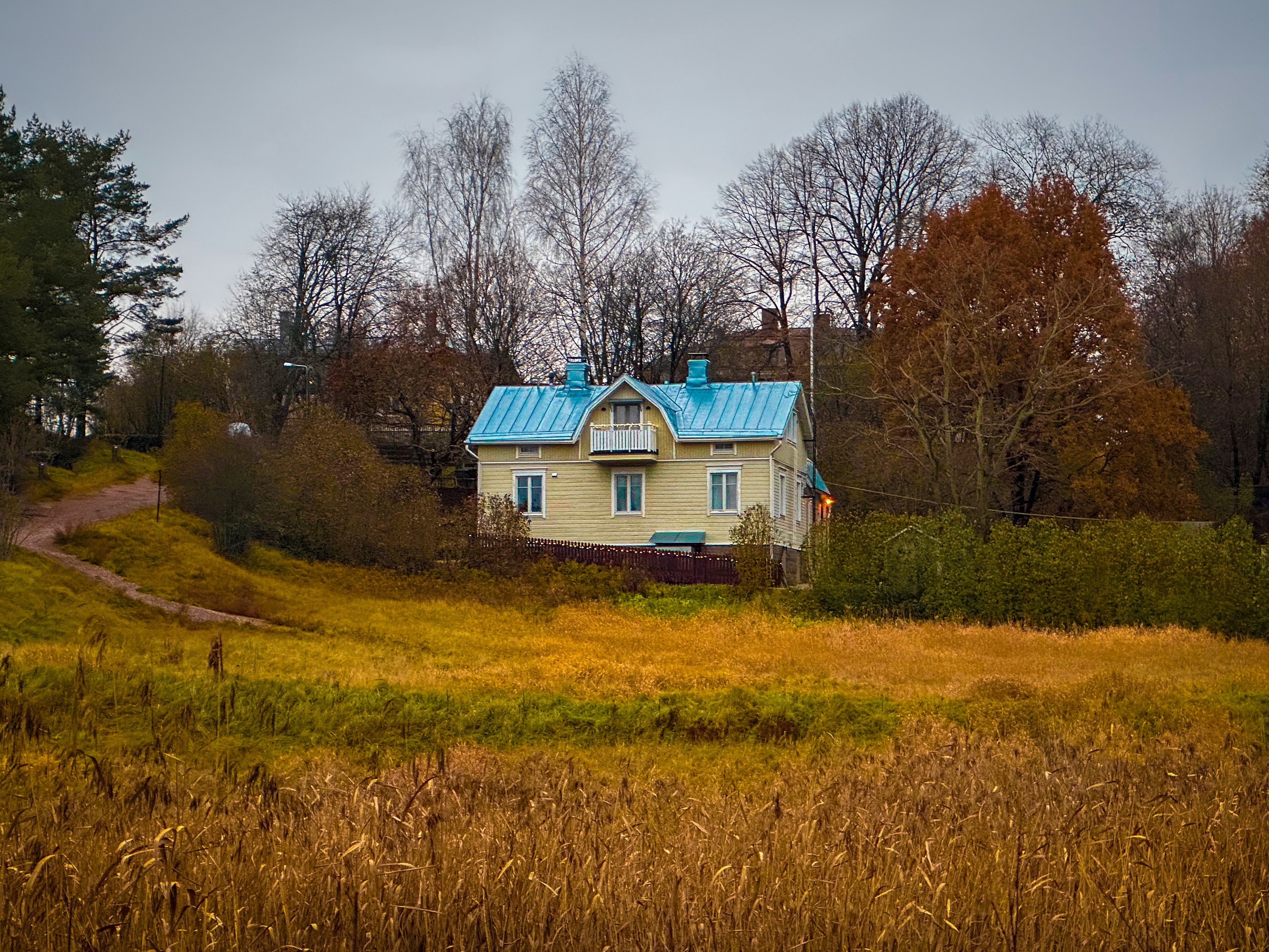 a yellow house with a blue roof in a field
