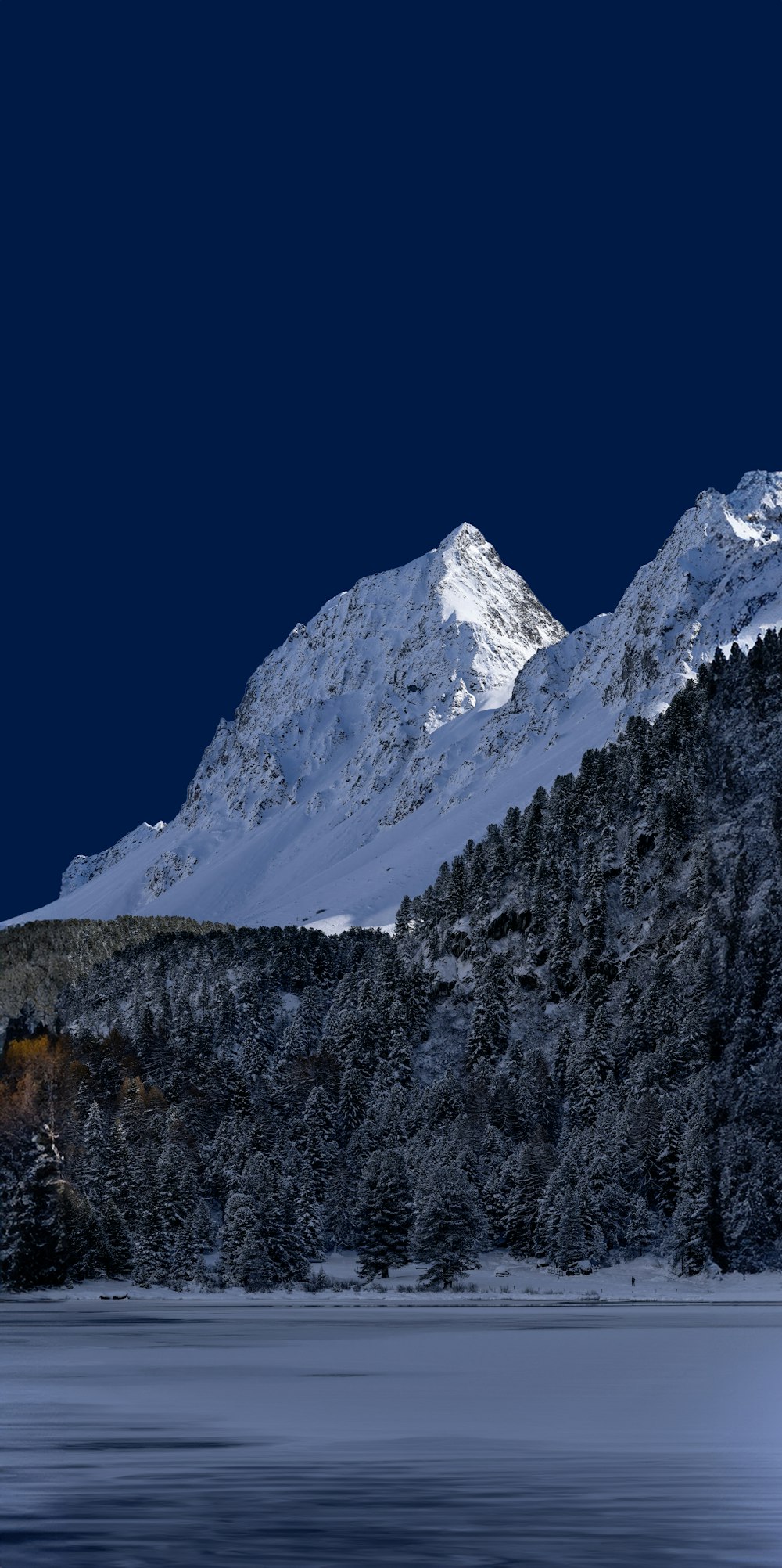 a mountain covered in snow next to a body of water