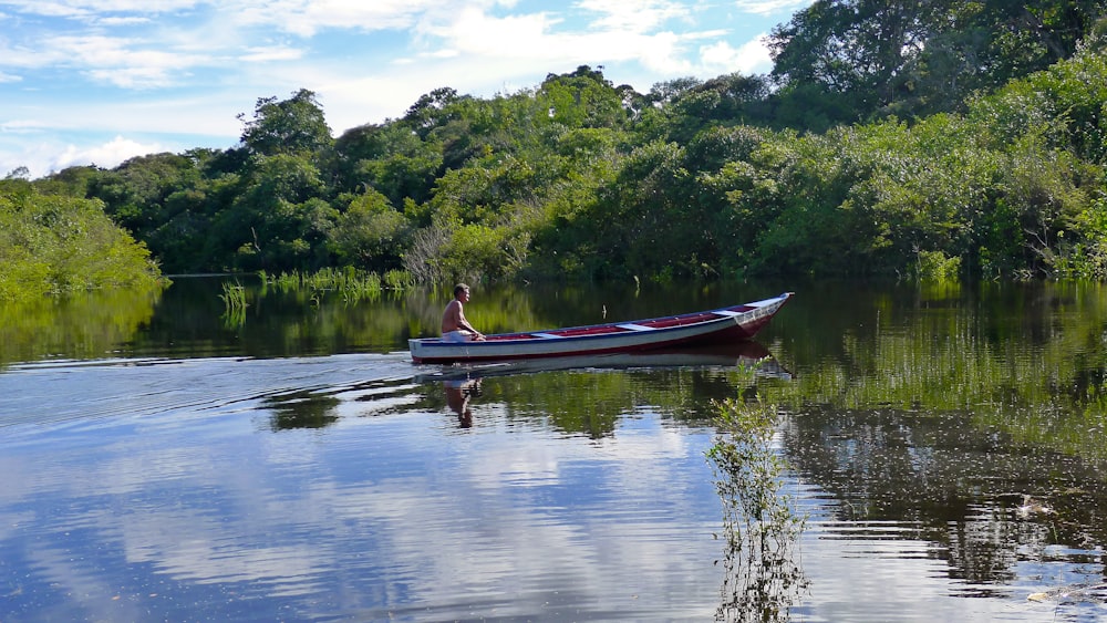 a man in a red and white boat on a river