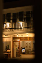 A night view of the café’s exterior glowing warmly against the dark city backdrop.