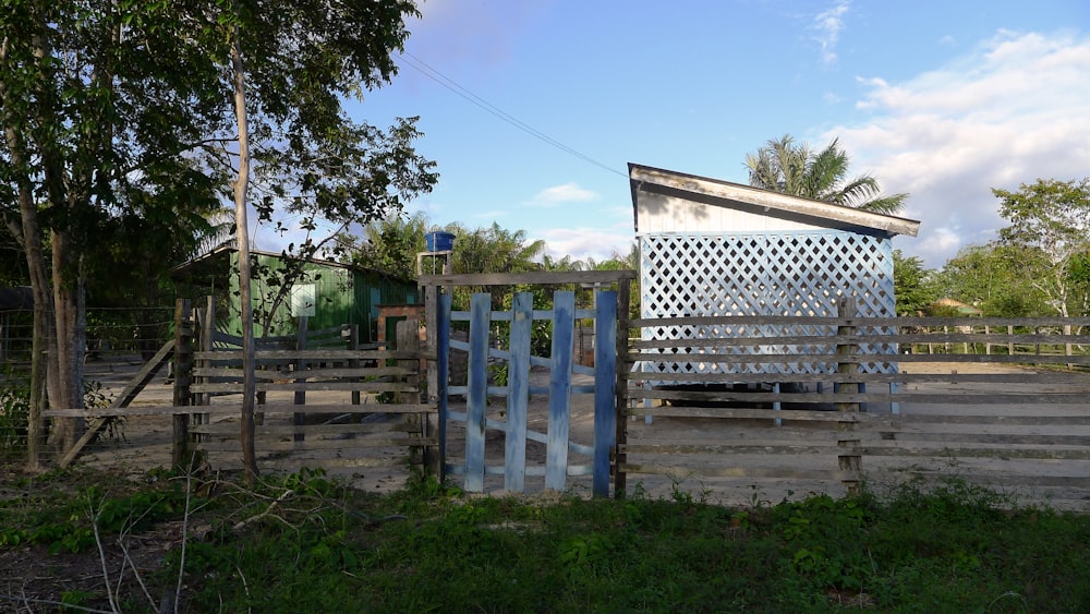 a wooden fence with a metal gate and a building in the background