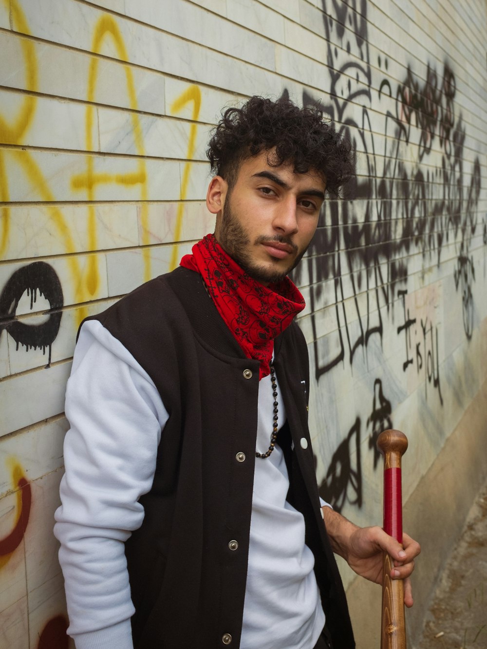 a man standing next to a wall with graffiti on it