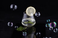 Close-up of hands holding a glass of infused water with lemon and mint.
