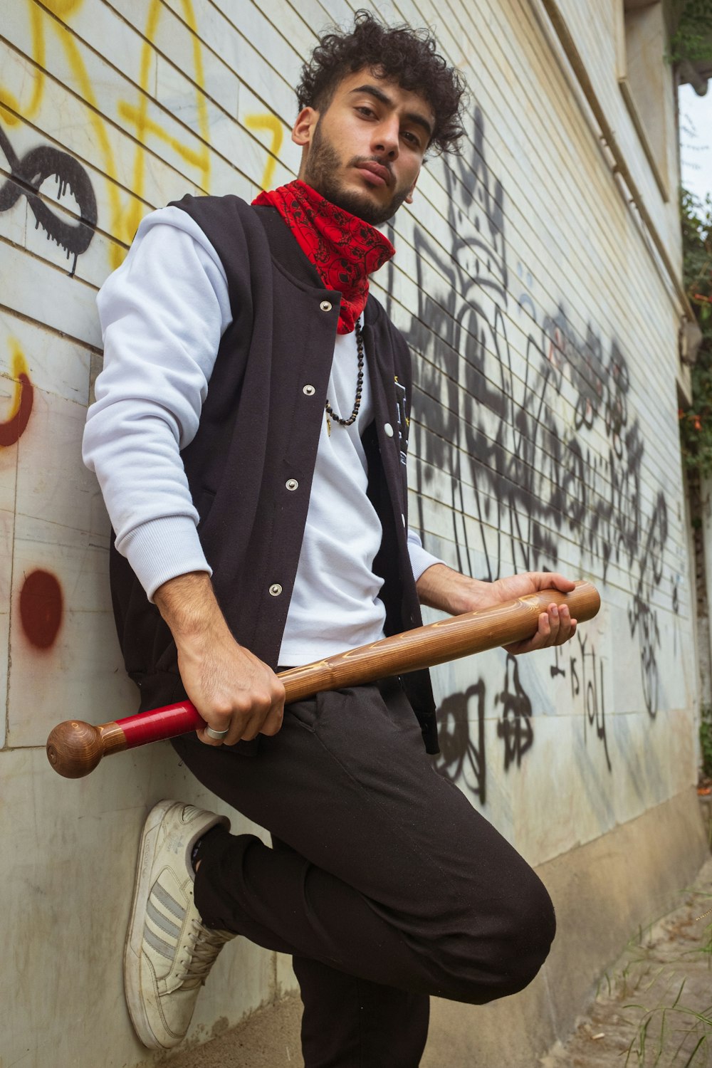 a man leaning against a wall with a baseball bat
