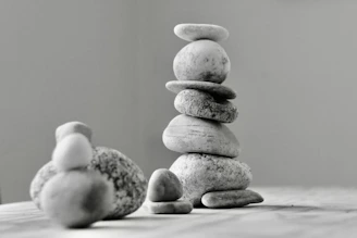 Close-up of smooth stones stacked in balance on a soft beige surface.