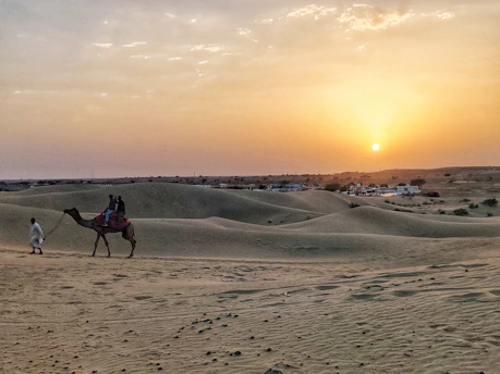two people riding a camel in the desert