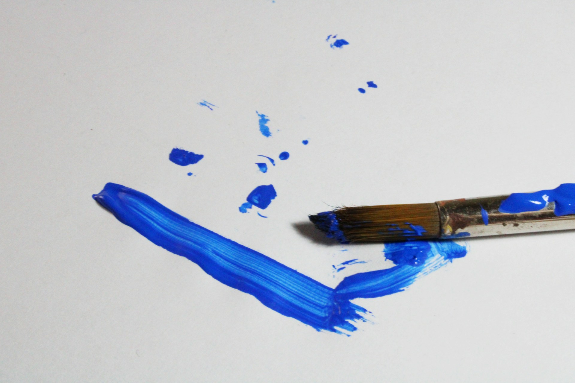 a paintbrush with blue paint on a white surface