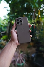 Close-up of a hand holding a vibrant phone case against a blurred outdoor background.