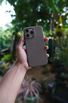 Hands holding a smartphone with a stylish protective case outdoors.