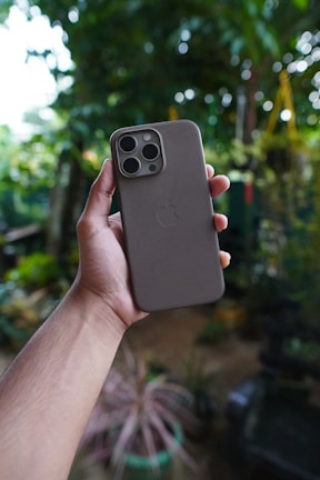 Hands holding a phone with a stylish protective case outdoors.