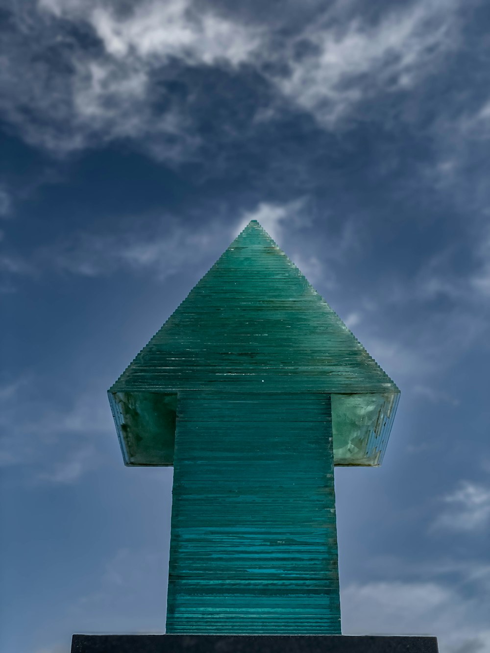 a tall green building with a sky background