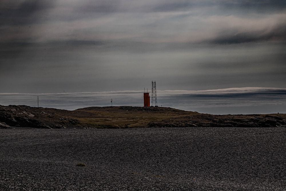 a red tower sitting on top of a hill under a cloudy sky