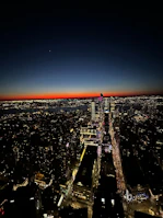 Drone footage showcasing a dynamic urban skyline under deep blue twilight with illuminated windows.