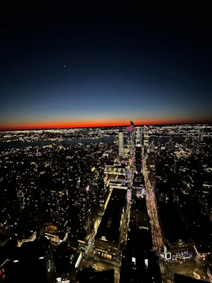 Drone footage showcasing a dynamic urban skyline under deep blue twilight with illuminated windows.