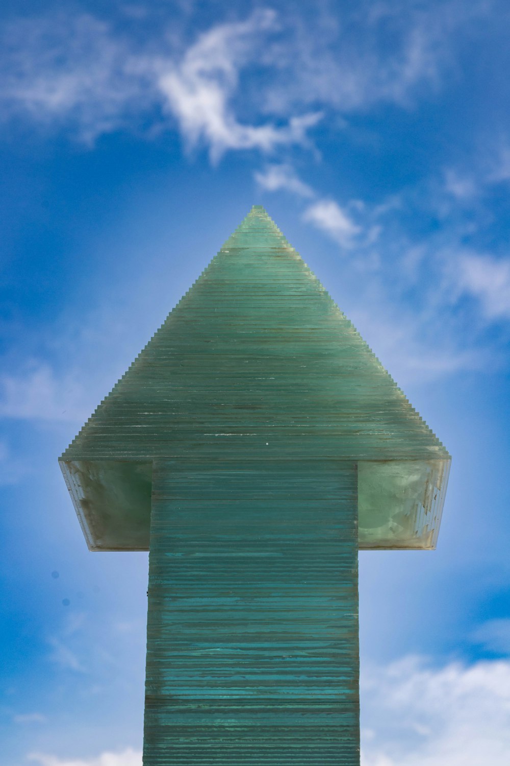 a tall green building with a sky in the background