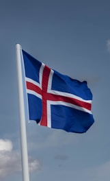 a flag flying in the wind with a blue sky in the background