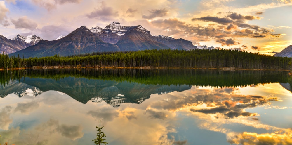 a mountain range is reflected in the still water of a lake