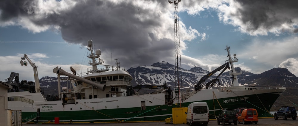 a green and white boat sitting in a harbor