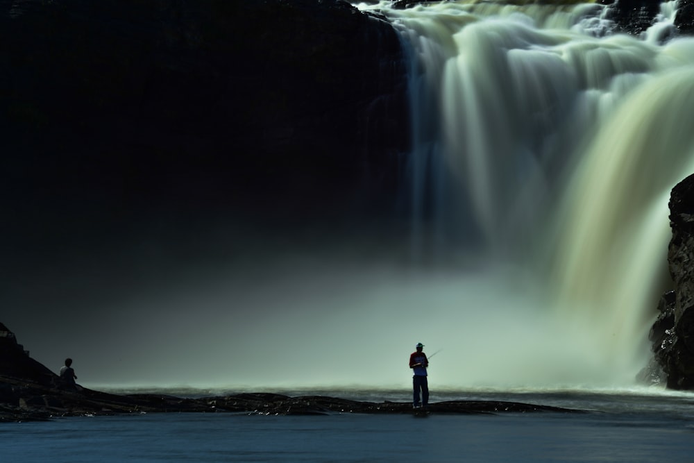 a man standing in front of a waterfall