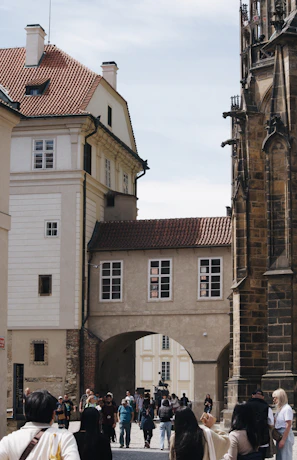 A scenic European street with students walking and chatting, framed by historic architecture.