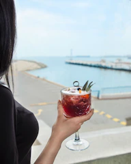 A bartender handing a tropical cocktail to a happy cruise guest at the ship's bar.