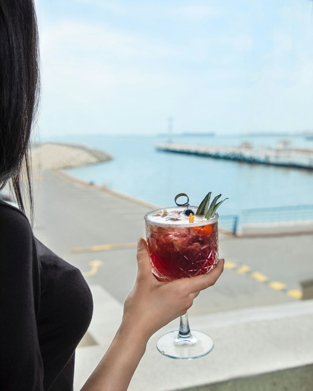 a woman holding a wine glass with a drink in it