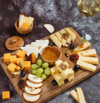 a wooden cutting board topped with cheese and grapes