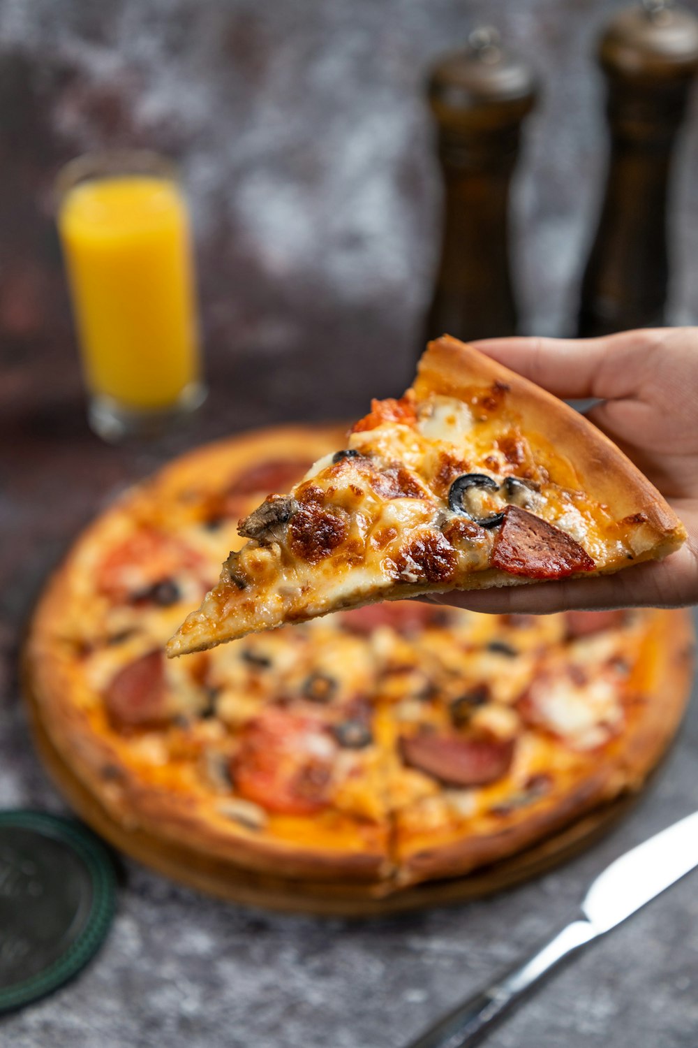 a person holding a slice of pizza in their hand