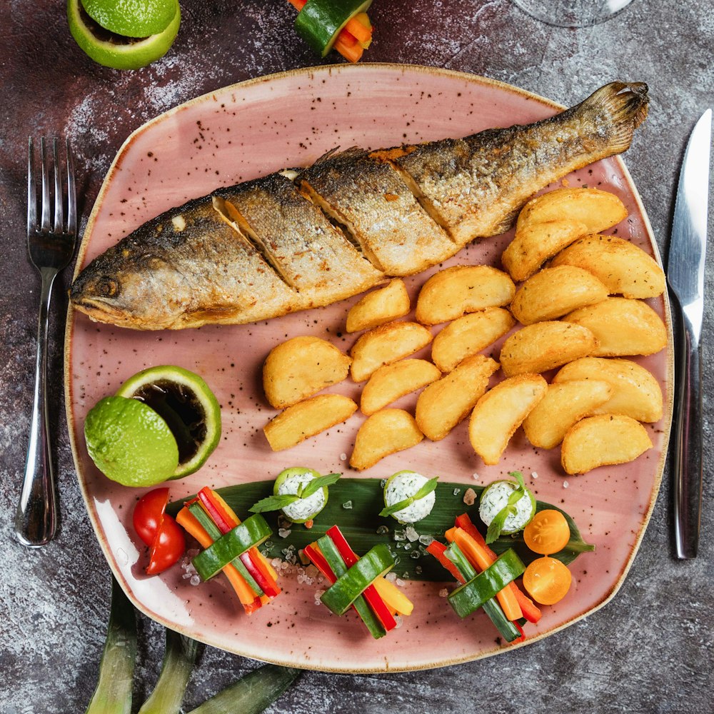 ein rosafarbener Teller mit Fisch und Gemüse