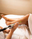a woman laying on top of a bed with a hair dryer