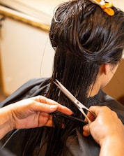 a woman cutting another woman's hair with scissors
