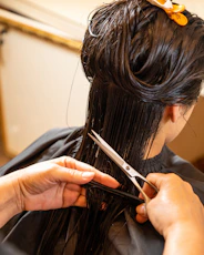 a woman cutting another woman's hair with scissors