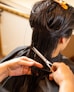 a woman cutting another woman's hair with scissors