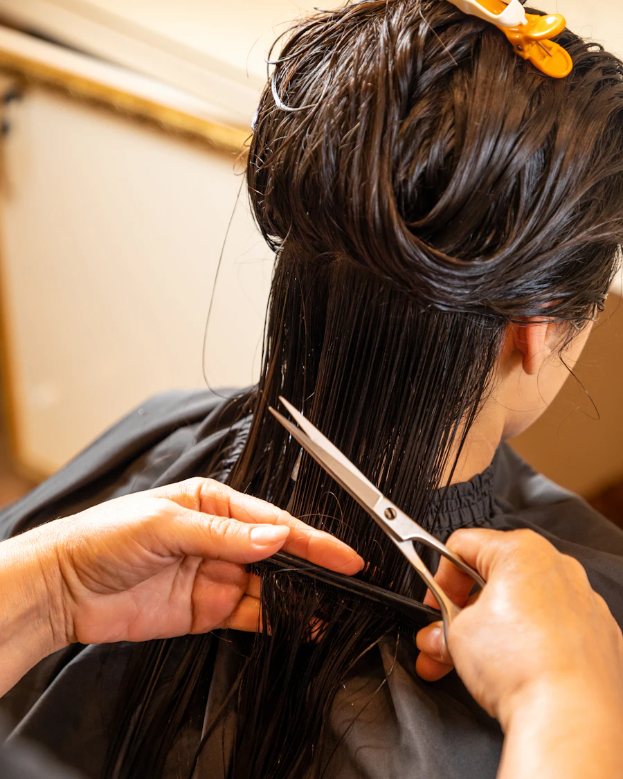 Coiffeuse coupant aux ciseaux les cheveux d'une cliente
