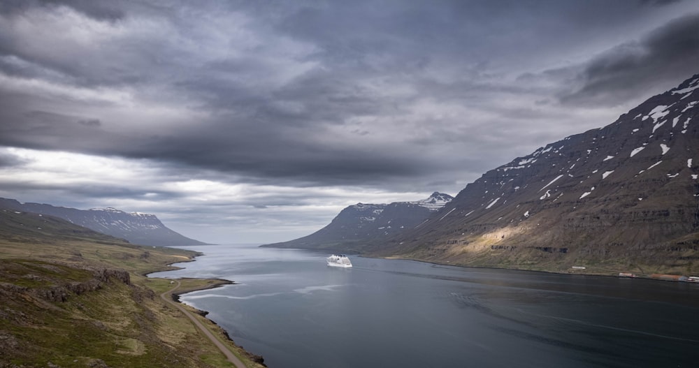 a body of water surrounded by mountains under a cloudy sky