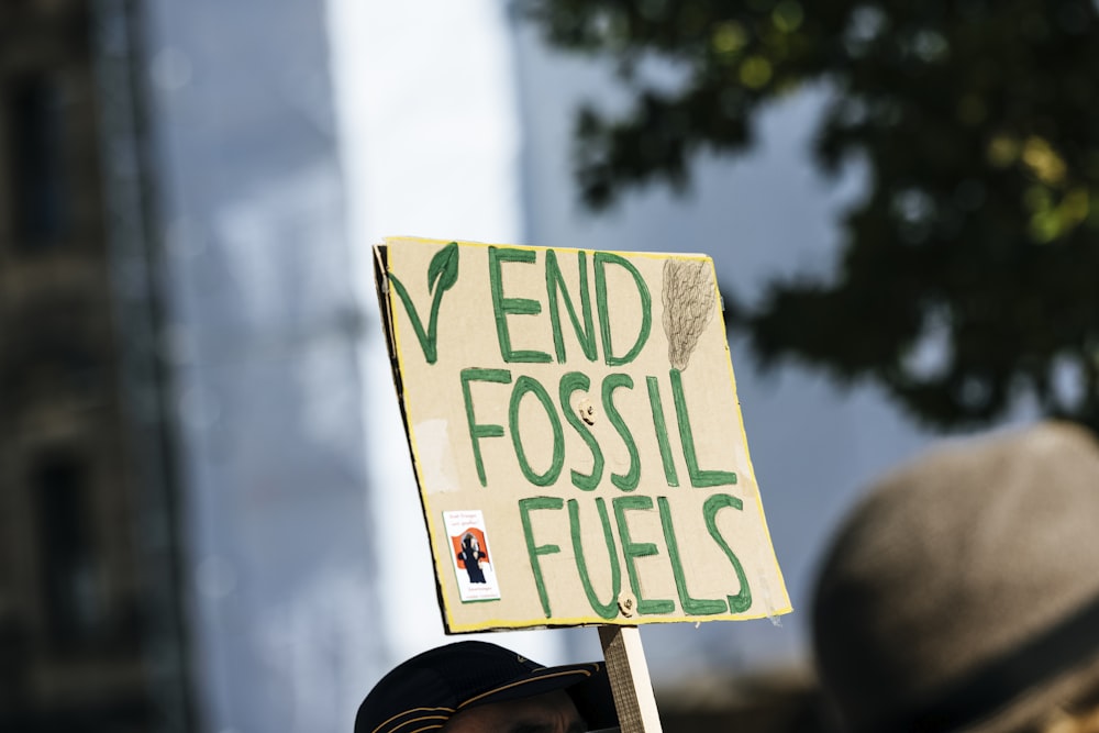 「化石燃料をやめろ」と書かれた看板を掲げる人