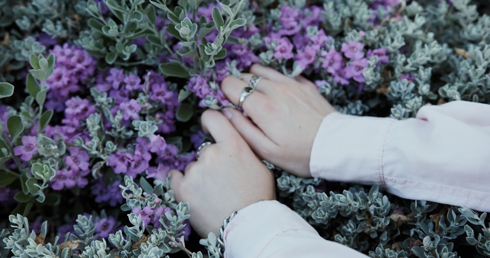 two hands touching each other with purple flowers in the background
