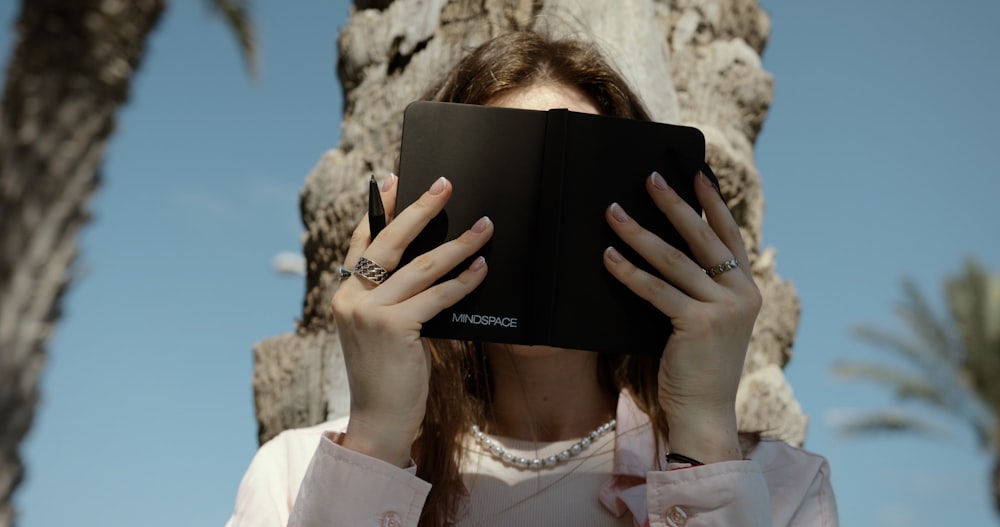 a woman covering her face with a book