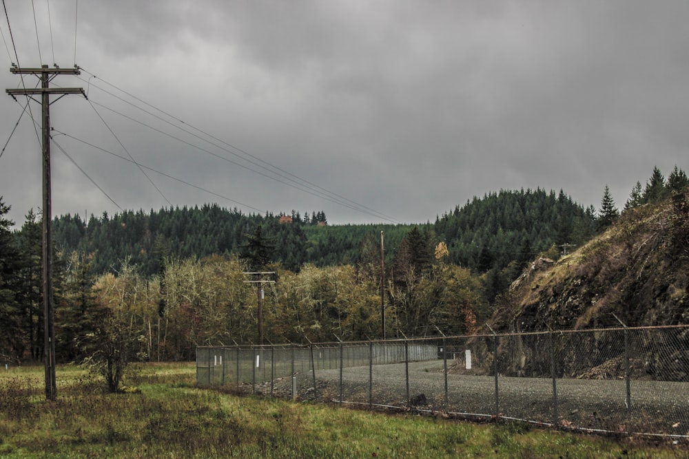 a fenced in area with a forest in the background