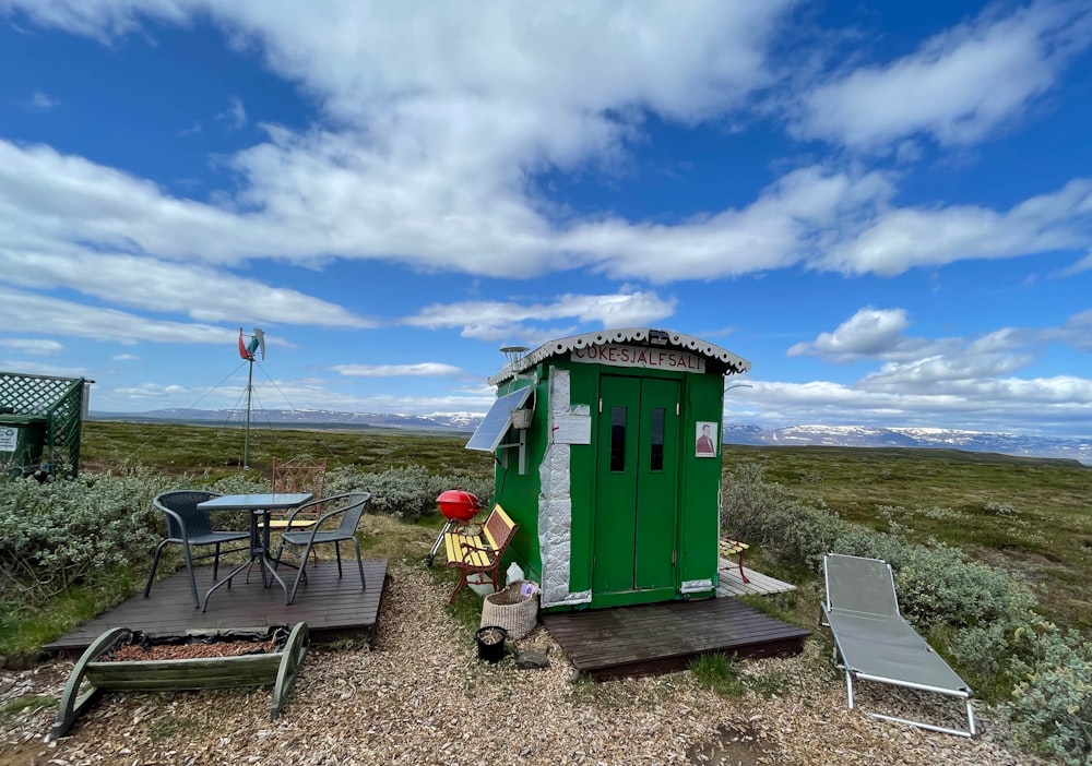 a man sitting in front of a green portable toilet