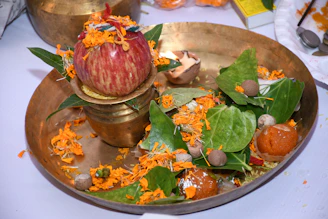 Brass kalash decorated with intricate beadwork placed beside traditional puja items on a wooden altar.