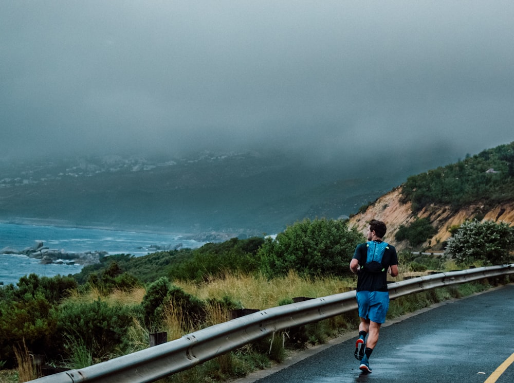 a man running down a wet road next to the ocean