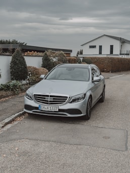 Discreet luxury car parked beside a sleek modern residence with expansive glass walls.