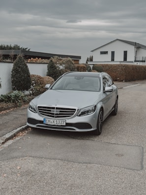 Discreet luxury car parked in front of a modern concrete and glass residence at dusk.